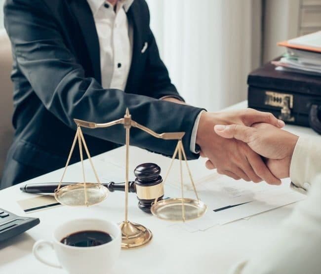 Legal consultation handshake with scales of justice on a desk